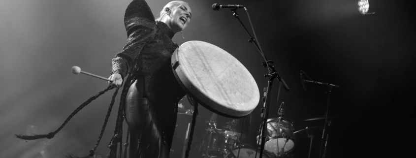 Black & white photo of Eivør holding a big pale framedrum and drumstick