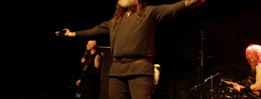 Vansind frontman J Asgaard with arms spread wide toward the audience during a concert